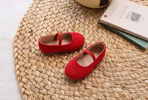 Detail of red suede Mary Jane flat for girls with elastic strap on a woven mat