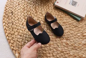 Detailansicht der mattschwarzen Mary Jane Schuhe für Mädchen mit Wellenrand und Klettverschluss