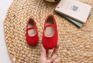 Detailed close-up of red suede children's Mary Jane shoes on a natural woven mat