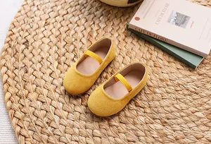 Detail of yellow candy-colored girls' Mary Jane shoes with textured fabric on a woven mat