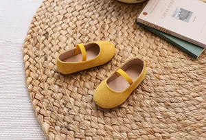 Detail shot of yellow canvas Mary Jane shoes for girls on a warm rustic background