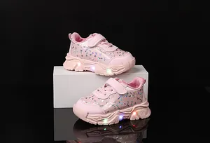 Détail de chaussures roses pour bambins avec nœuds à paillettes et semelles LED colorées