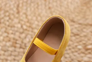 Detailed macro view of yellow suede girls Mary Jane shoes with elastic strap and inner lining