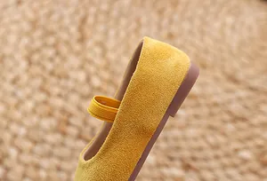 Close-up of yellow suede girls' Mary Jane shoes featuring elastic strap and rubber sole