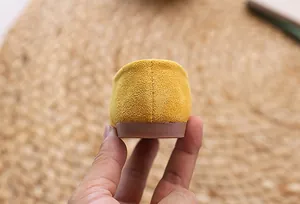 Detailed close-up of ginger yellow suede flat shoes showcasing heel stitching texture