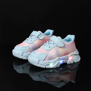 Scarpe sportive bimbi con sfumatura rosa blu e suole LED luminose su riflesso nero
