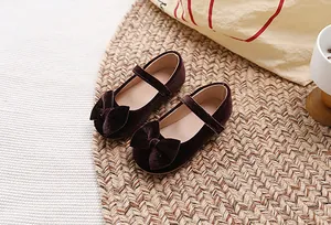 Detail van bordeauxrode fluwelen Mary Jane schoenen met strik en klittenband voor meisjes