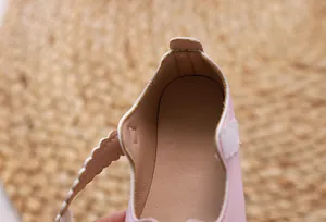 Detail von rosa Mädchenschuhen aus Kunstleder mit Wellenrand und Klettverschluss