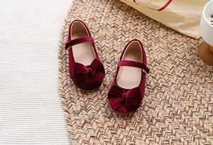 Detail van bordeauxrode fluwelen Mary Jane meisjesschoenen met strik en klittenband