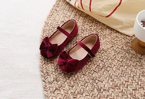 Detailweergave van bordeauxrode fluwelen Mary Janes voor meisjes met decoratieve strikken