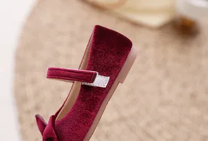 Detailopname van meisjes bordeauxrode fluwelen Mary Jane schoenen met strik en klittenband