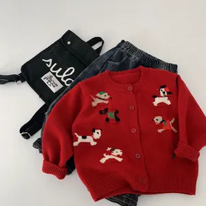 Dettaglio di cardigan in maglia rossa con motivi a cucciolo e pantaloni in denim