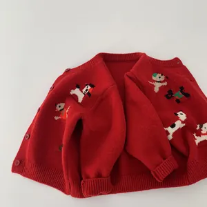 Dettaglio del cardigan rosso in maglia con motivi di cani cartoon e polsini a costine