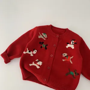 Dettaglio del cardigan rosso in maglia con polsini a coste e motivi jacquard di cani