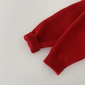 Dettaglio ravvicinato di un cardigan in maglia rossa con polsino a coste e trama morbida