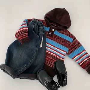 Flat lay of striped hooded knit sweater with denim pants and black buckle shoes