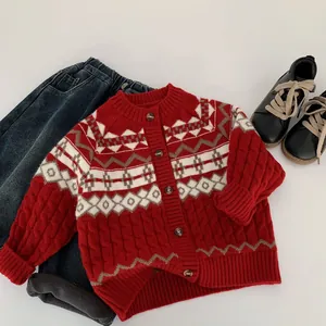 Flat lay of red jacquard knit cardigan with geometric patterns and denim jeans