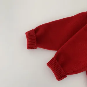 Close-up of red knit sweater sleeve showing detailed ribbed cuffs and soft fabric texture