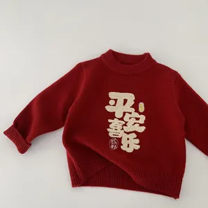 Detail of red kids knit sweater with festive calligraphy embroidery and ribbed cuffs