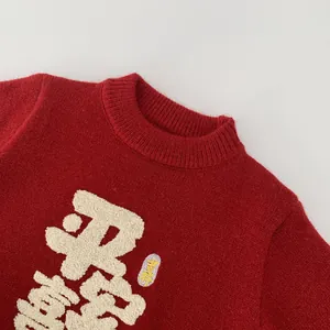 Close-up of red festive kids sweater featuring white plush embroidery with Chinese characters