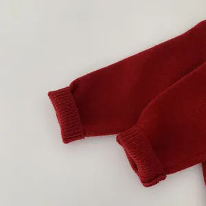 Close-up of vibrant red knit sweater featuring elastic ribbed cuff and fine texture