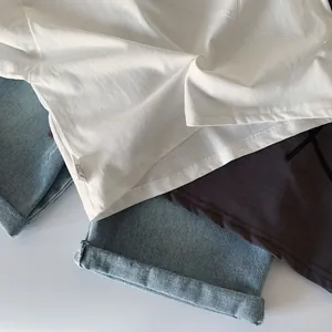 Flat lay of boys white and dark grey cotton T-shirts with washed blue denim shorts