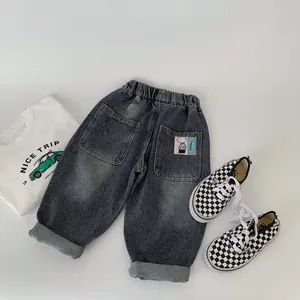 Detailed view of kids denim pants with elastic waistband and cartoon patch on back pocket