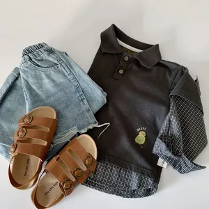 Detail of boys' polo shirt with faux layered plaid trim and embroidered bird pattern