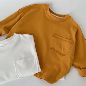 Dettaglio di magliette a maniche lunghe in cotone giallo e bianco con taschini
