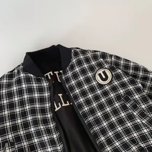 Detail of checkered bomber jacket with rib collar, zipper, and embroidered U badge