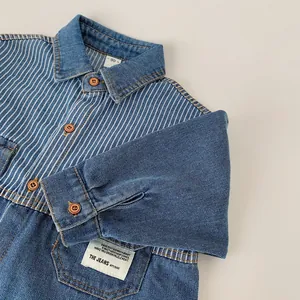 Detail of children's denim shirt with striped patchwork, brand tag, and brown buttons