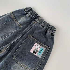 Detail of kids washed denim pants with elastic waist and Charlie Brown cartoon patch
