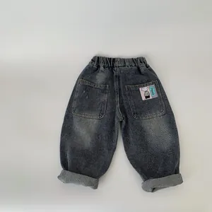 Detail view of boys' denim trousers with elastic waist and cartoon patch on the back pocket