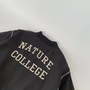 Detail of the back of a black jacket featuring white NATURE COLLEGE embroidery and piping