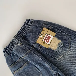 Detail of dark blue washed denim jeans with elastic waist and branded back pocket patch