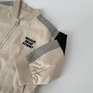 Detail of embroidered WEAVE BEAR STUDIO logo on color-block kids bomber jacket