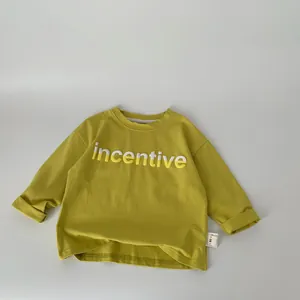 Detail of mustard yellow kids t-shirt with incentive lettering and size tag