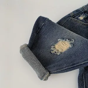 Detailed macro view of dark blue denim jeans with distressed holes and cuffed leg hems