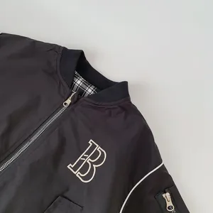Detail of black bomber jacket with letter B embroidery and checkered lining