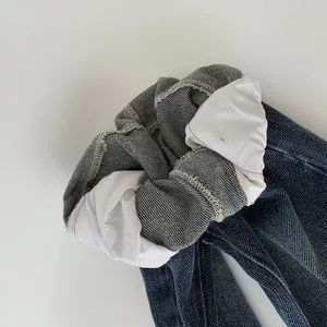 Detailed view of dark blue denim scrunchie showing stitching and white cotton lining