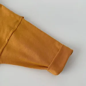 Dettaglio macro della manica in maglia giallo zenzero con risvolto e cuciture a vista