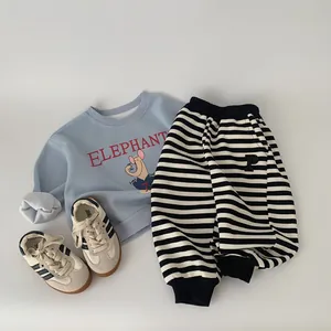 Flat lay of boys light blue elephant sweatshirt with black striped jogger pants and sneakers
