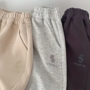 Détail du pantalon de jogging enfant avec taille élastique et broderie de lettres en trois tons