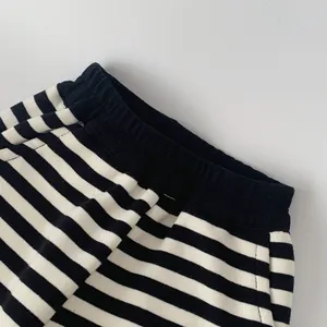Detail view of elastic ribbed waistband and side pockets on striped kids sports pants