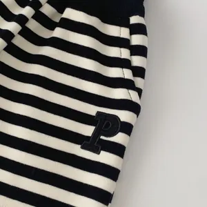 Detail of boys' black and white striped sports pants with side pocket and P-patch embroidery