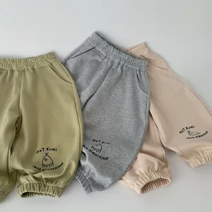 Dettaglio di pantaloni in cotone per bambini in verde avocado, grigio e albicocca