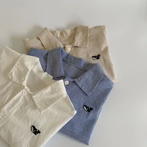 Detail of kids shirts with whale embroidery in beige, blue and khaki stripes
