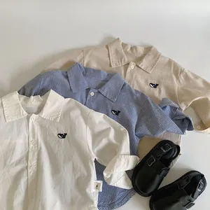 Flat lay of kid shirts with whale embroidery in white and striped blue patterns