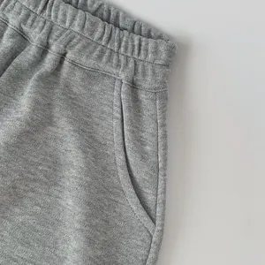 Dettaglio della vita elasticizzata e della tasca laterale su pantaloni grigi per bambini