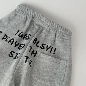 Dettaglio dei pantaloni sportivi grigio melange per bambini con tasca posteriore e stampa